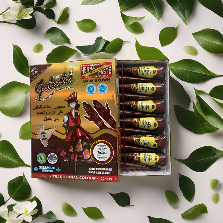 Boîte ouverte de cônes de henné Golecha de couleur marron foncé, présentée avec des feuilles de henné fraîches et des fleurs, symbolisant l'authenticité et la tradition.
